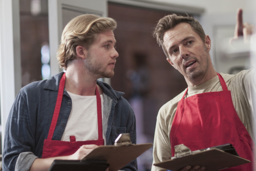 Kollegen im Supermarkt mit Klemmbrettern und digitalen Tablets